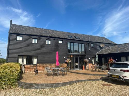 a large black house with a patio and a pink ribbon at Wheatsheaf Barn in Manningtree