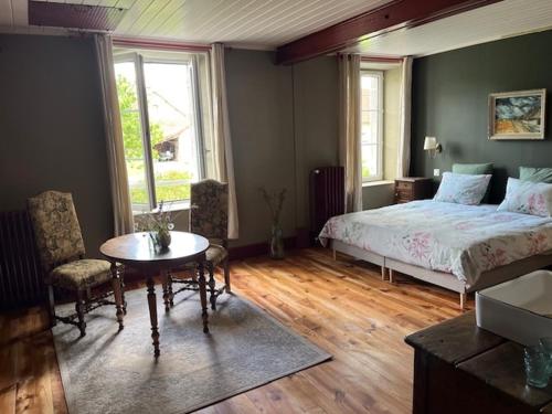 a bedroom with a bed and a table and chairs at Moulin de Maupoy in Saint-Symphorien-de-Marmagne