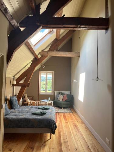 a attic room with a bed and a couch at Moulin de Maupoy in Saint-Symphorien-de-Marmagne