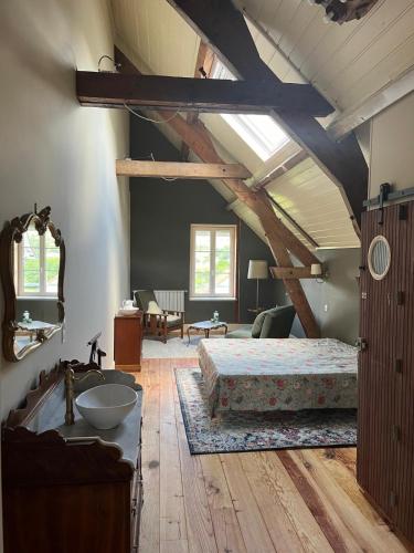 a bedroom with a bed and a ceiling with beams at Moulin de Maupoy in Saint-Symphorien-de-Marmagne