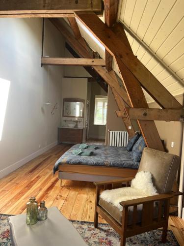 a bedroom with a bed and a chair in a room at Moulin de Maupoy in Saint-Symphorien-de-Marmagne