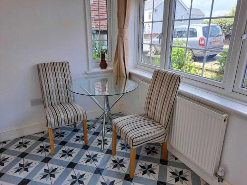 a dining room with a glass table and two chairs at AcLand Lodge Dovercourt West in Harwich