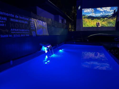 a pool with blue lights in a room with a tv at Apartament 2 dormitoare LUX situat la parter in complex ApartHotel Botosani 3 in Botoşani