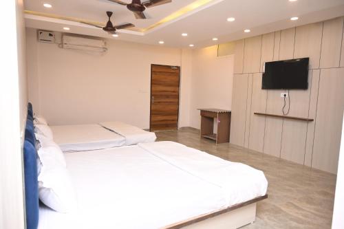 a bedroom with two beds and a flat screen tv at Radhyam Retreat in Ayodhya