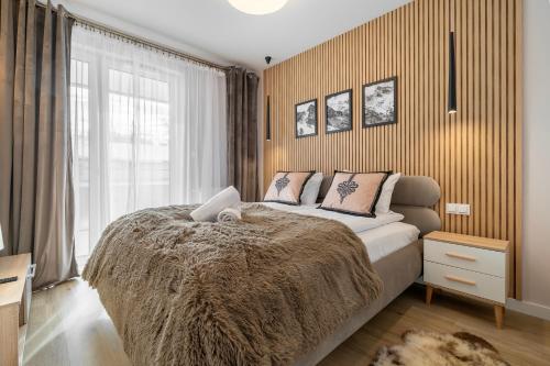 a bedroom with a large bed and a window at RentPlanet - Apartamenty Zakopiańskie in Zakopane