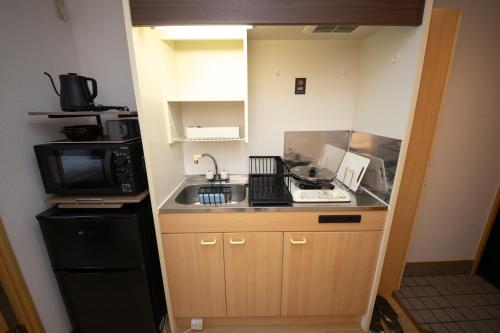 a small kitchen with a sink and a microwave at goom Monthly Nakasu Maxim in Fukuoka