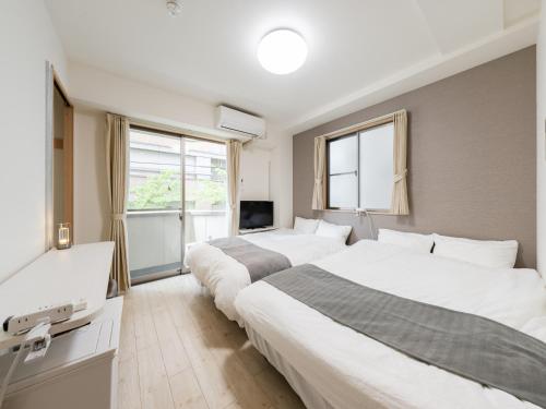 two beds in a hotel room with a tv at Ikebukuro 10 min-Family-Friendly Stay-Mobile Wi-Fi&Switch-Net in Tokyo