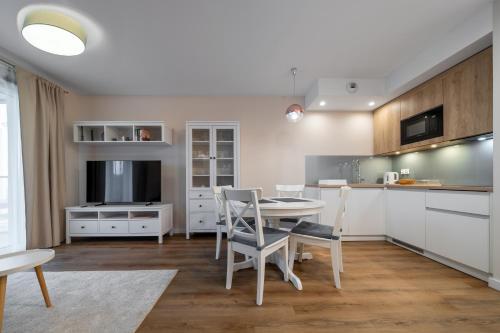 a kitchen with white cabinets and a table and chairs at RentPlanet - Apartamenty Zakopiańskie in Zakopane