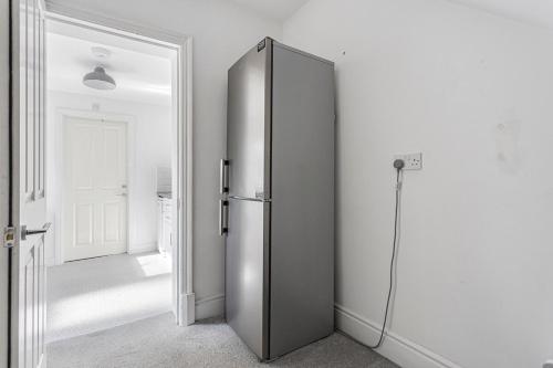 a large silver refrigerator in a white room at Bright Garden Flat in Ashford Town with Free Parking in Ashford