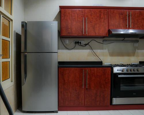 a kitchen with a stainless steel refrigerator and wooden cabinets at O2 pool villa in Ras al Khaimah