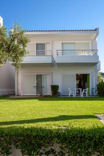 a white house with a lawn in front of it at Akrotiri apartment in Pefkochori