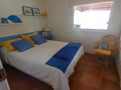 a bedroom with a bed with blue and yellow pillows at Chalet Playa Portonovo in Sanxenxo