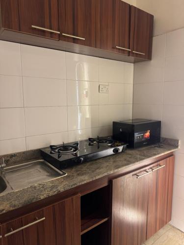 a kitchen with a stove and a microwave at Zimmy Apartment in Ankuru