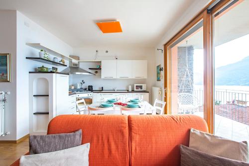 an orange couch in a kitchen with a table at La Breva - Terrazzo panoramico vista lago di Como in Dorio
