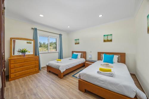 a bedroom with two beds and a dresser and a mirror at Villa Monte Velho in Albufeira