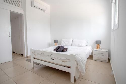 a white bedroom with a white bed and two lamps at 2BD Garden Apartment in Paphos City