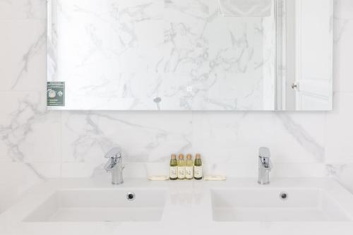 a white bathroom with a mirror and a sink at Château de Bayssan in Béziers