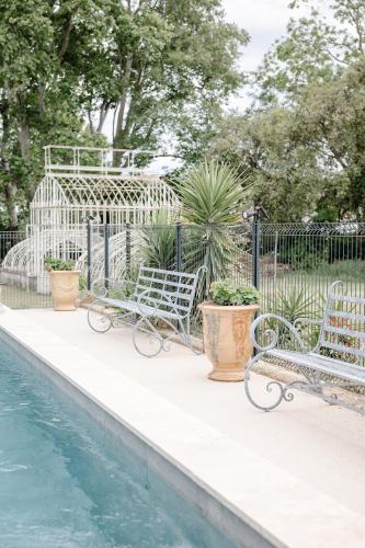 - deux chaises assises à côté de la piscine dans l'établissement Château de Bayssan Maison d'hôtes, à Béziers