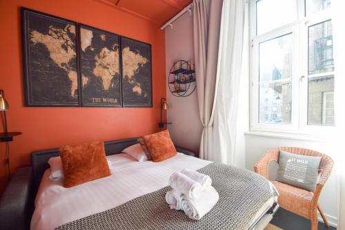 - une chambre avec un lit aux murs orange et une fenêtre dans l'établissement L'Orange Malouine - Studio 2 people with WiFi, à Saint-Malo