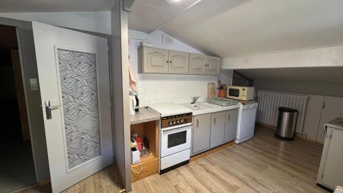 une cuisine avec des armoires blanches et un four à plaques de cuisson dans l'établissement La Faucille 3, à Praranger