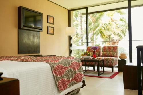 a bedroom with a bed and a chair and a window at EKHO Safari Tissa in Tissamaharama