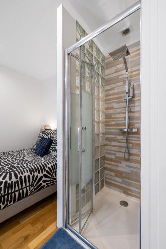 La salle de bains est pourvue d'une douche en verre et d'un lit. dans l'établissement Nice Renting - 5 Massena - Elegant Air-Conditioned Cocoon Quiet Patio Massena, à Nice