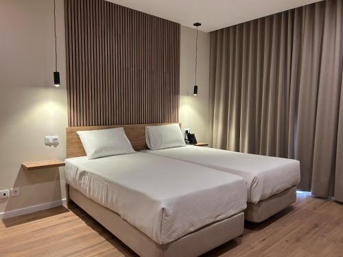 a bedroom with a large bed with white sheets at Hotel Caldas Internacional in Caldas da Rainha