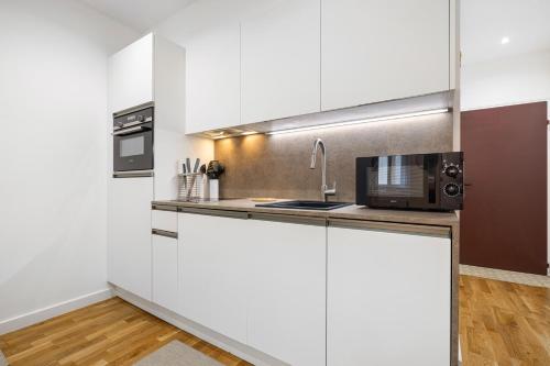 une cuisine avec des armoires blanches et un micro-ondes dans l'établissement Nice Renting - 5 Massena - Elegant Air-Conditioned Cocoon Quiet Patio Massena, à Nice