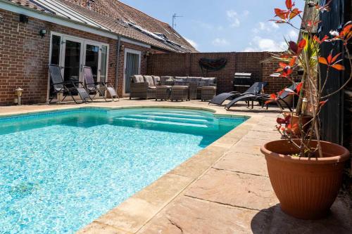 a swimming pool with a potted plant next to a house at Villa Hobland Barn in Fritton