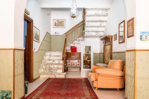 a living room with an orange chair and a staircase at Hotel Marnie in Massarosa