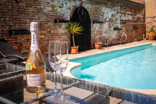 a bottle of wine and two glasses next to a swimming pool at Villa Hobland Barn in Fritton