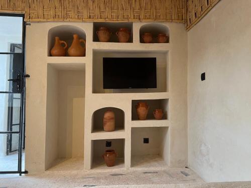 a room with vases and a tv on a wall at Riad Ait Sonia in Tamraght Ouzdar