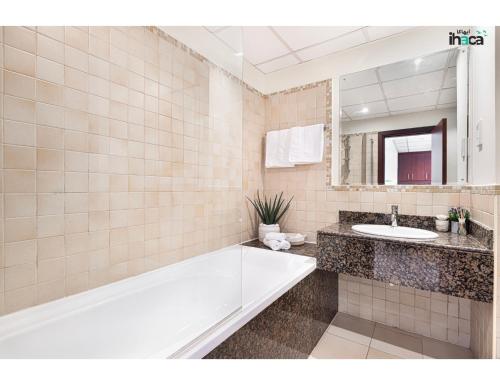 a bathroom with a tub and a sink and a mirror at Boho Studio Beachfront Ain Sea View JBR Walk 1min in Dubai