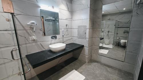 a white bathroom with a sink and a shower at Hotel Luxurio - In-House Barista Cafe, Near Golden Temple Amritsar in Amritsar