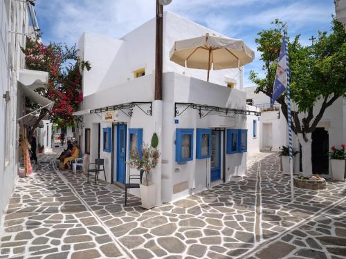 a white building with blue doors and an umbrella at Yellow Stone in Kampos Paros