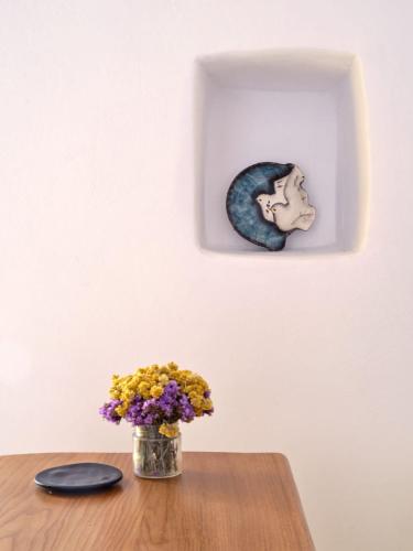 a vase of flowers on a table with a picture of a head at Yellow Stone in Kampos Paros