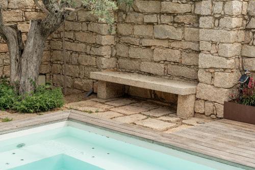 a stone wall with a bench next to a pool at Villa dell'800 con Jacuzzi Privata - San Pantaleo in San Pantaleo
