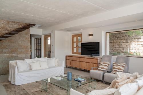 a living room with a white couch and a tv at Villa dell'800 con Jacuzzi Privata - San Pantaleo in San Pantaleo