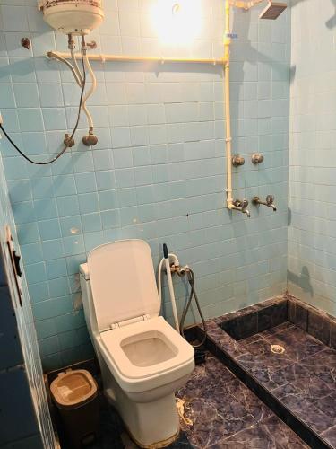 a bathroom with a toilet and a blue tiled wall at Goaround Homes Kalkaji, South Delhi in New Delhi