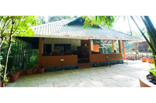 a small building with a bench in a courtyard at Holiday Courtyard Wayanad in Padinjarathara