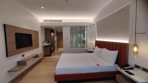 a bedroom with a large bed and a television at Mirage Hotel, Mumbai International Airport in Mumbai