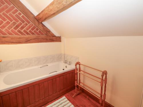 a bathroom with a bath tub in a attic at Horse Shoe Cottage in Bradley in the Moors