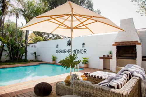 Una sombrilla y sillas junto a una piscina. en Osborne Manor Luxury Guesthouse, en Kimberley
