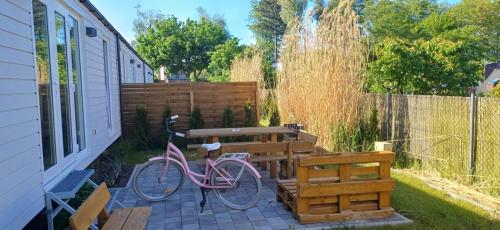 una bicicletta rosa parcheggiata accanto a una panchina di legno di Domki & Pokoje Władysławowo a Władysławowo