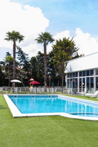 a swimming pool in front of a building with palm trees at Hotel Caldas Internacional in Caldas da Rainha