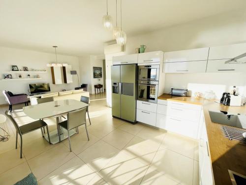 une cuisine avec des armoires blanches et une table et une salle à manger dans l'établissement Apartment Center Sea View Garage Conciergerie, à Sanary-sur-Mer