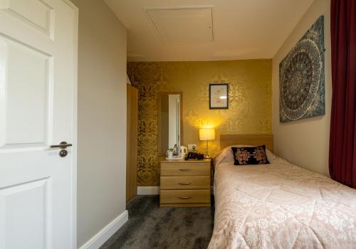 a bedroom with a bed and a dresser with a lamp at Brockley Hall Hotel in Saltburn-by-the-Sea
