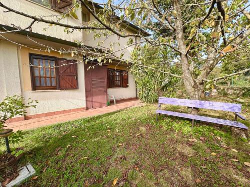 a wooden bench sitting in front of a house at La casa nel Bosco in Manziana