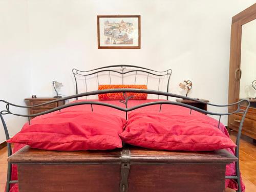a bed with red pillows on top of a wooden chest at La casa nel Bosco in Manziana