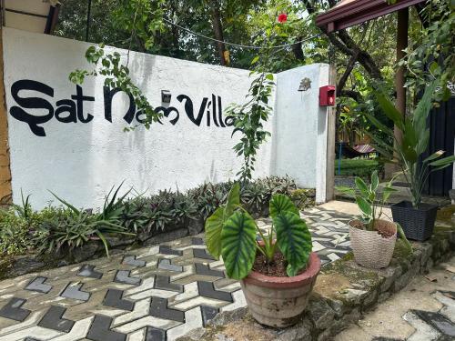 a sign with a potted plant on a sidewalk at Sat Nam Village Hotel in Sigiriya